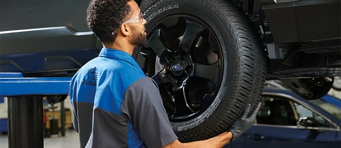 A Subaru service technician checking tires.