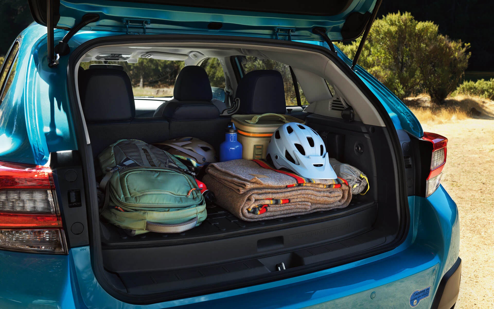 A backpack, blanket, and bike helmet in the rear cargo area of a Crosstrek Hybrid | Stevens Creek Subaru in Santa Clara CA